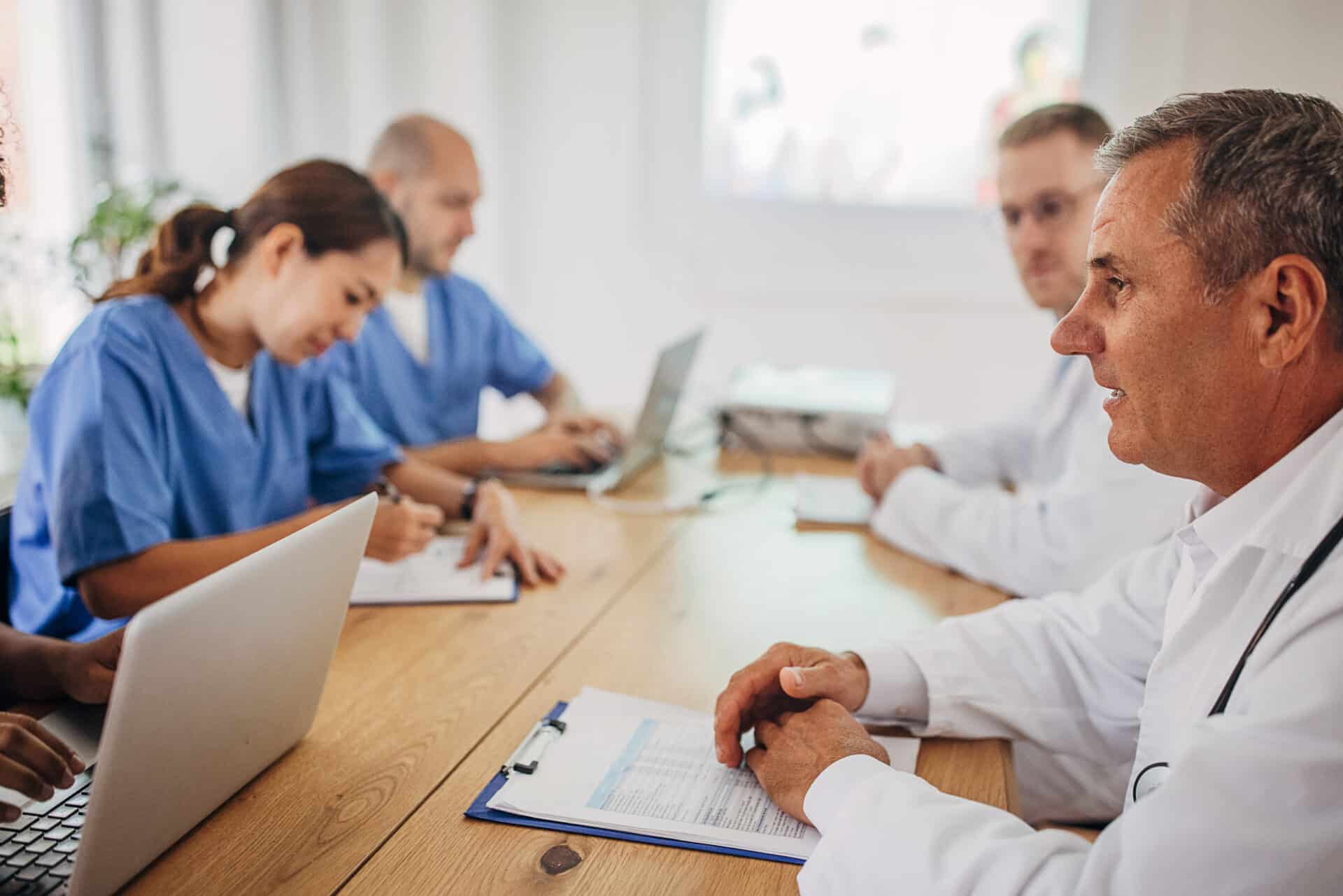 Group of doctors and nurses sitting at large table and having a seminar or lecture