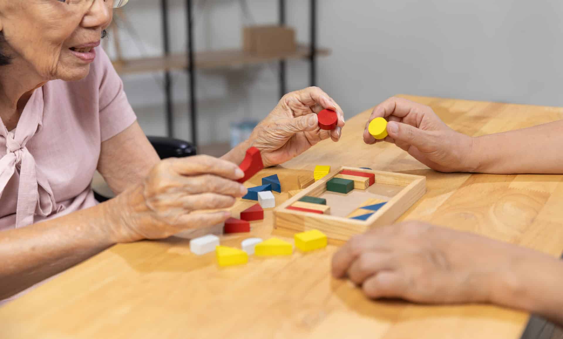 Woman playing wooden shape puzzles game with therapist. Photo: iStock